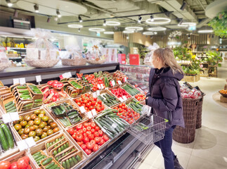 Woman buying vegetables(tomatoes and cucumbers) at the market