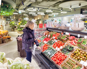 Woman buying vegetables(tomatoes and cucumbers) at the market