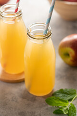 Apple juice glass bottles, with fresh red apples, wooden background.