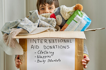 Happy kid supporting a box with humanitarian aid for a natural disaster victims