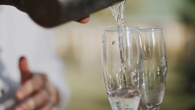 Bartender pours cocktails into glasses. Bar in the open space.