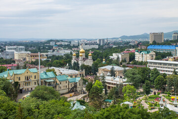 Cityscape - panoramic top view of the historical part of Pyatigorsk in Russia with buildings and green trees against the background of Mount Beshtau on a cloudy summer day