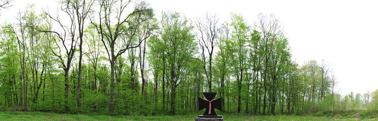 Summer panoramic landscape with mixed forest and ancient cross.