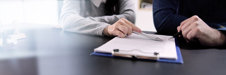 Two Businesspeople Hand Analyzing Document Over Glass