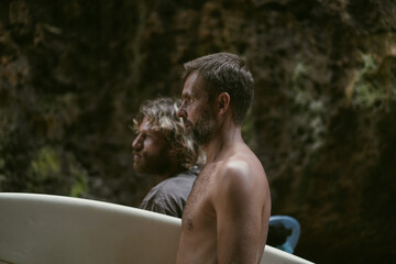 Man with a surfboard goes to the Uluwatu surf spot.