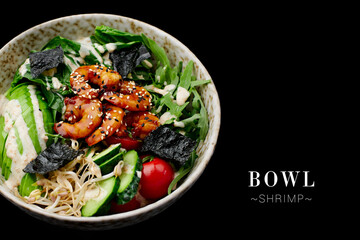 Side view of seafood bowl with black tiger shrimps sliced cucumber and avocado, arugula leaves, cherry tomatoes and nori seaweed served in bowl isolated on black background. banner with text space.