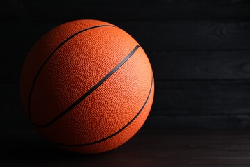 Obraz premium Basketball ball on wooden table against dark background, space for text