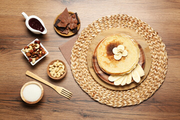 Delicious crepes with different products on wooden table, flat lay
