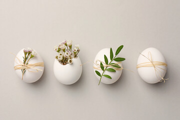 Festive composition with chicken eggs and natural decor on light grey background, flat lay. Happy Easter