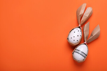 Easter bunnies made of craft paper and eggs on orange background, flat lay. Space for text
