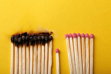 Burnt and whole matches on yellow background, flat lay