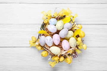 Festively decorated Easter eggs on white wooden table, top view