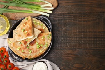Delicious fried chebureki with cheese, green onion and ingredients on wooden table, flat lay. Space for text
