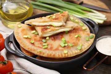 Delicious fried chebureki with cheese and green onion on wooden table