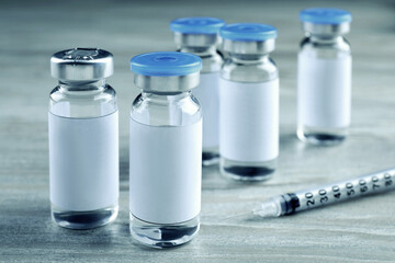 Medication in glass vials and syringe on white wooden table