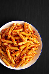 Homemade Penne With Tomato Sauce on a Plate on a black background, top view. Copy space.