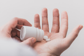 A close-up view of the hands with the pills. Dispensing pills from the bottle onto the palm of the hand