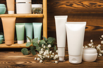 Skin care cosmetics on a brown wooden table. Cosmetic tubes in the bathroom. Cream, serum and face scrub. Facial care concept. MOCAP.