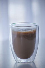 Coffee with milk in a transparent glass with a double bottom. A popular drink in an original glass.