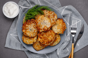 Close up view of potato pancakes. Potatoes pancakes latkes, flapjacks, hashbrown or potato vada on gray plate over gray wooden table, with fresh dill and sour cream. Copy space for text