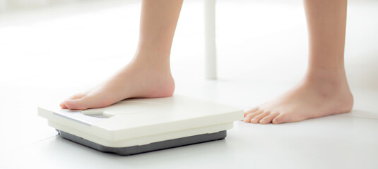 Closeup foot of woman standing on scales measuring for control weight in the room, overweight and...