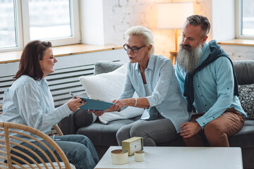 Senior couple, mature man and woman, husband and wife sitting on the sofa on the therapy session at psychologist cabinet, discussing stress, family problems. Concept of mental health care