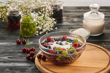 Preservation in jars with berries on a wooden table, a mix of blueberries, gooseberries, raspberries, black currants