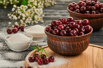 sugar for preservation in bowls on a wooden table, ripe cherries on the table