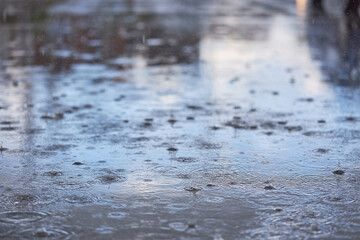 Heavy rain falling on the asphalt, puddles with splashes from drops..