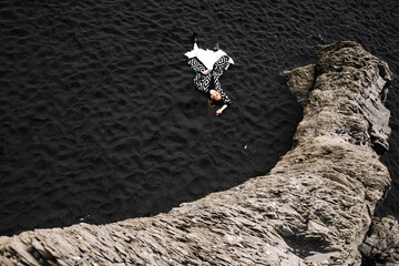 graphic photo of a girl lying on black sand