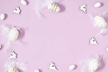 Easter holiday composition. Easter decorations beautiful easter eggs feathers bunny toy isolated on pastel purple background. Easter concept. Flat lay, top view, copy space