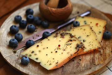 Cheese with black pepper on a wooden board.