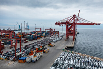 Various containers and cars waiting to be loaded onto the ship at the port.