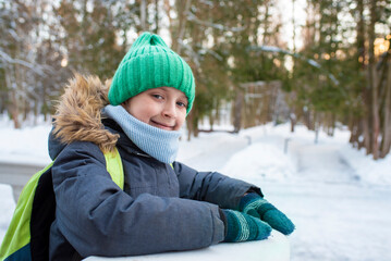 Fototapeta na wymiar portrait of a smiling boy in warm clothes and with a backpack in a snowy winter outside 