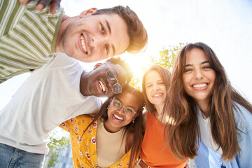 Happy Young friends looking camera and laughing. Smiling Group of people having fun together outdoors. Cheerful community of students university. Modern lifestyle of multicultural people joyful.