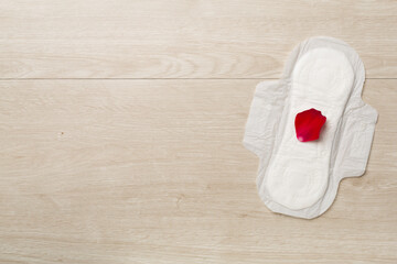 Menstrual pad with red petals on wooden background, top view © Liami