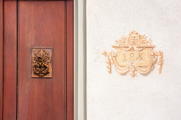 Close-up of golden hand-painted street number and copper door escutcheon plate in the French Quarter, Charleston, South Carolina. Wood and stucco.