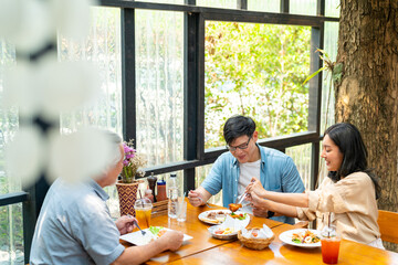 Happy Asian family couple and elderly father having lunch eating food together at cafe restaurant on summer holiday vacation. Family relationship, fathers day and older people health care concept.