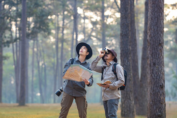 Team of the Asian naturalist looking at the map while exploring in the pine forest for surveying...