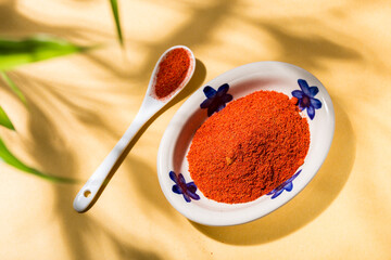 Tasty Spice: Paprika Powder in Ceramic Plate with Yellow Background and Natural Shades