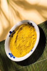 Yellow Comfort: Curry in Ceramic Bowl and Spoon with natural shadows, top view