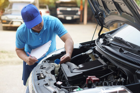 Close up mechanic holds paper clipboard to take note and check  engine of car. Concept, Car service and maintenance. Clain accident insurance.  