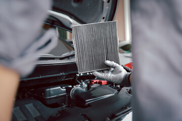 Auto mechanic checking, cleaning and replacing car air filter. Concept of car care service...
