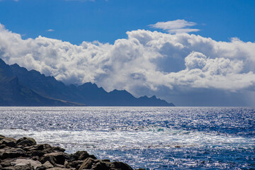 View from the natural pools on the ocean and hills and cliffs of Tamadaba Natural Park on the coast...