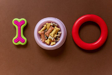 Close up of a Dog bones, bowl on brown background. Dog accessories, rubber toys. Minimalistic background.