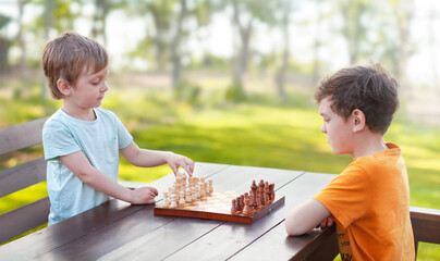 two brothers are playing chess outdoors	