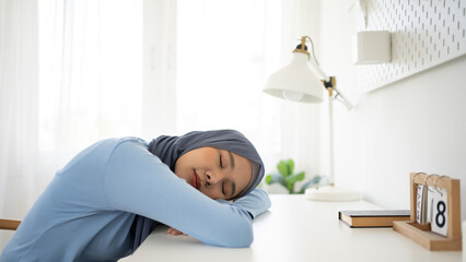 Young frustrated exhausted Muslim woman laid her head down on the table sit work at white desk.