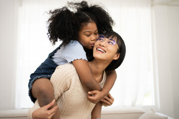 Smiling Asian mother holding adopted baby at home. Portrait of proud young woman rocking infant while looking at camera. Beautiful mixed race babysitter carrying adorable little child at home.