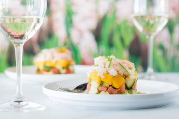 Fresh crab stack salad with mango and vegetables, served with white wine.