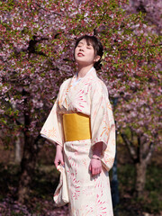 Portrait of beautiful young Chinese girl in Japanese kimono posing eyes closed with blossom cherry flowers background in spring garden, beauty, emotion, lifestyle, expression and people concept.